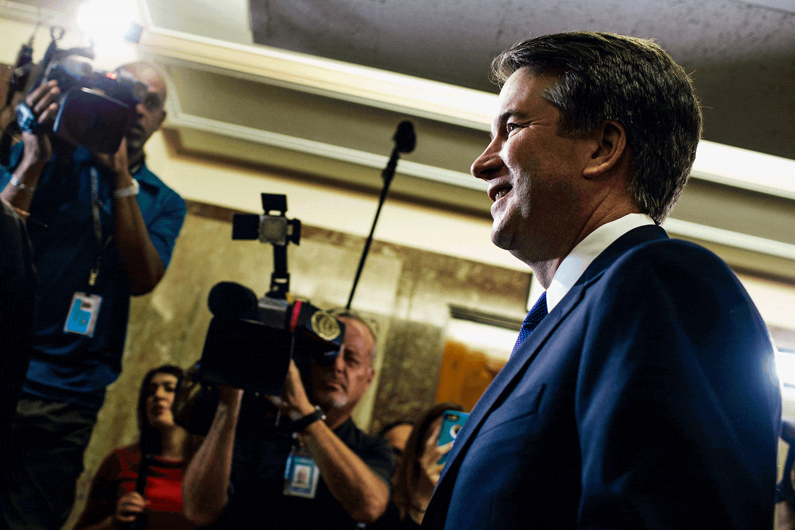 Brett Kavanaugh surrounded by reporters and photographers in a hallway.